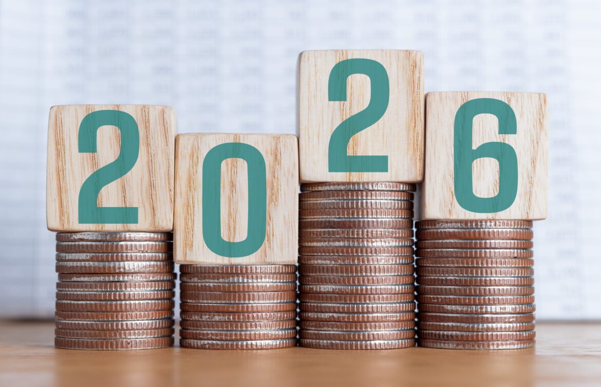 Wooden blocks showing ‘2026’ placed on stacks of coins of different heights, representing future interest rate changes in the US, UK and Europe